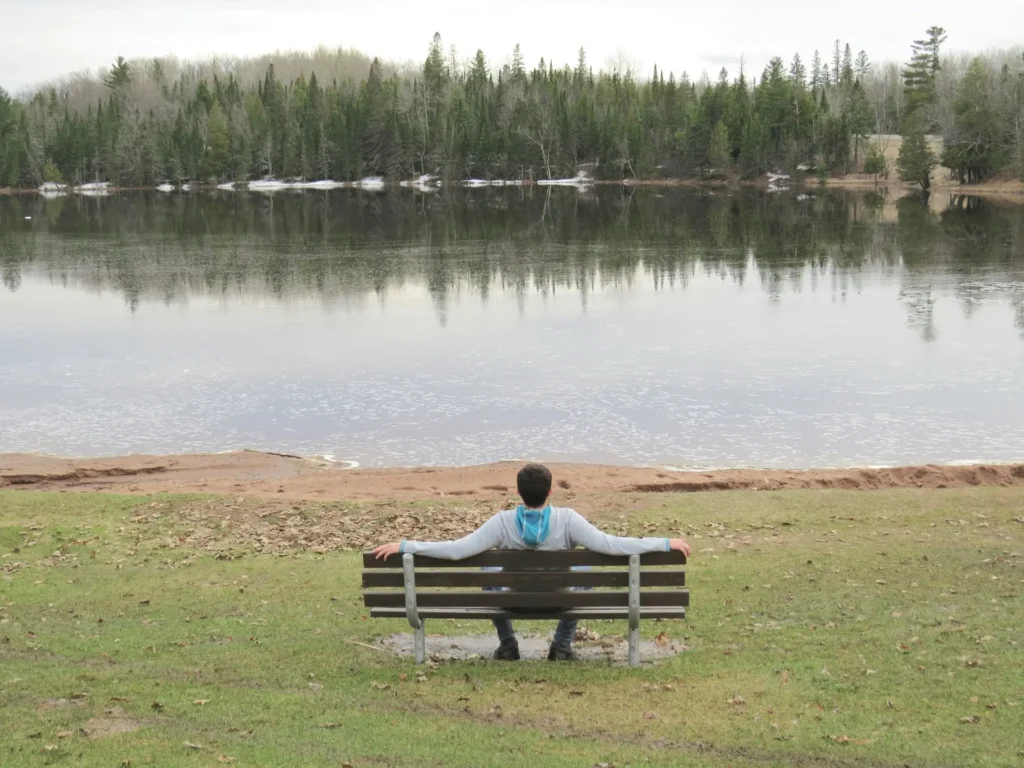 Person resting on a bench in front of a lake